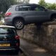 Unexplainable crash: Car left balanced on top of wall and Fiat 500