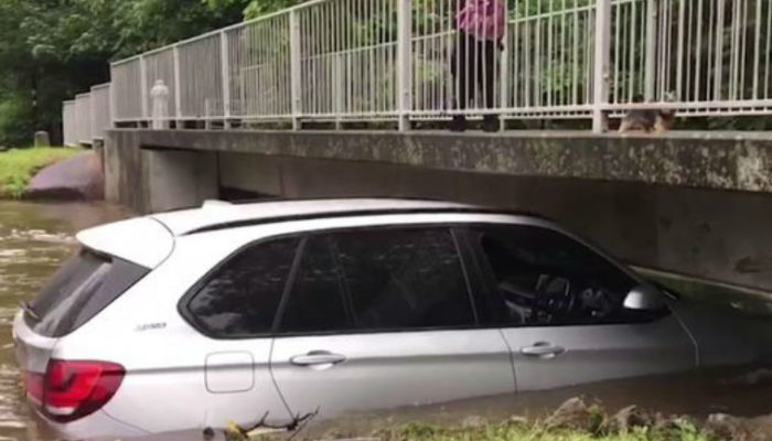 Video: £60k BMW X5 swept away by flood and left wedged under bridge